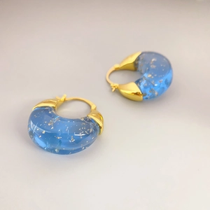 Modern gold hoop earrings featuring transparent blue resin with gold foil fragments
