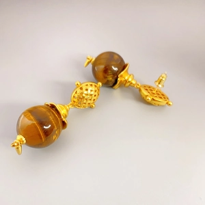 Macro detail of French vintage earrings with golden woven metal and tiger eye stones