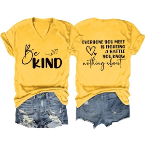 Flat lay of yellow V-neck tee with Be Kind print and distressed denim shorts set