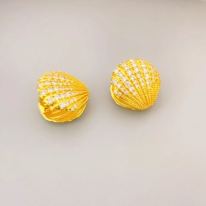 Macro detail of gold fan-shaped shell earrings with pave-set zircon stones and secure clasp