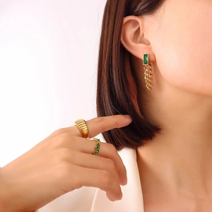 Eleganti orecchini a goccia verde smeraldo e set di anelli d'oro indossati da modella