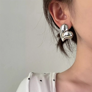 Chic silver heart stud earrings with liquid metal finish on female model's ear