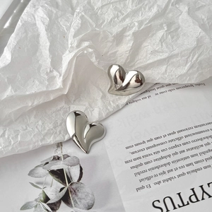 Polished silver heart-shaped stud earrings in a minimalist 3D design on a modern background