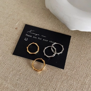 Gold and silver bamboo style hoop earrings set on rustic linen background