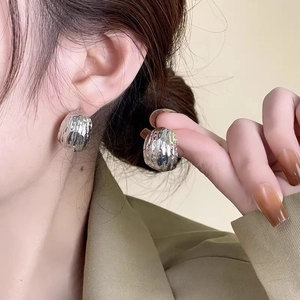 Silver geometric C-shaped textured stud earrings with lava molten metal finish on model