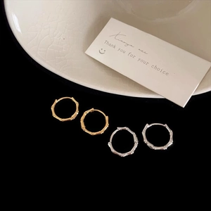 Bamboo-style minimalist hoop earrings in gold and silver finish set on a black background