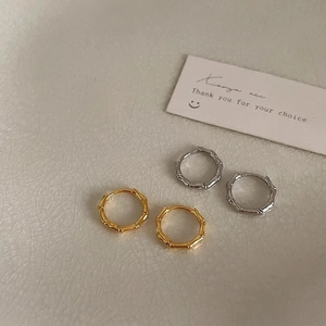 Bamboo style gold and silver hoop earrings on a light textured background with card