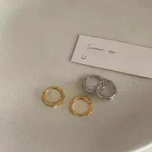 Detail view of gold and silver bamboo style hoop earrings on a white ceramic tray
