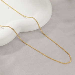 Collier en acier titane plaqué or 18 carats sur un support ondulé blanc artistique