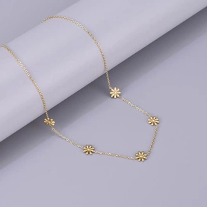 Collier marguerite minimaliste en acier titane doré sur un fond violet doux