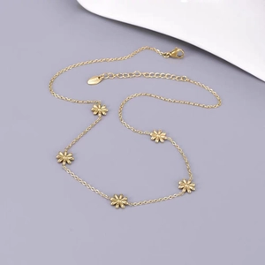Collier en acier titane doré orné de cinq délicats pendentifs en forme de marguerite