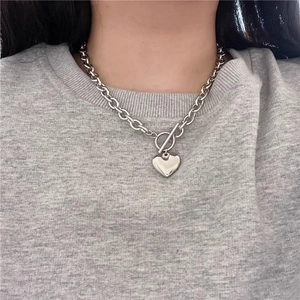 Collana con pendente a cuore in argento con catena spessa e chiusura a T su una modella