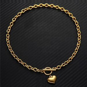 Collana cuore in acciaio al titanio dorato con chiusura a T su sfondo nero strutturato