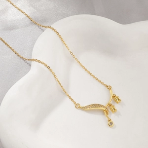 Collier muguet doré avec accents de zircon sur un socle en céramique blanche