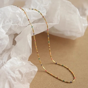 Collier bohème en perles émaillées colorées avec barres en acier titane doré sur papier