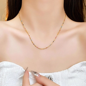 Collier bohème en tubes dorés avec perles colorées porté sur le cou pour un look chic