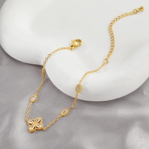 Elegantes goldenes Kleeblatt-Armband mit Zirkonia auf grauem Seidenhintergrund