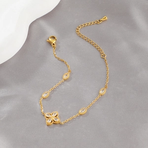 Elegantes goldenes Kleeblatt Armband mit Zirkonia-Anhängern auf seidigem Hintergrund