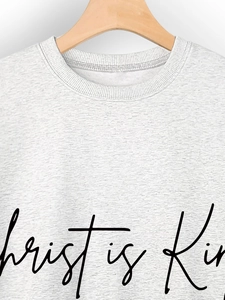 Close-up of gray crewneck sweatshirt with black Christ is King lettering and ribbed collar