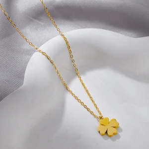 Detailed view of a gold clover pendant necklace on a decorative white tray with soft lighting