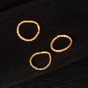 Three minimalist 18k gold starry textured stackable rings on black fabric background