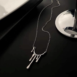 Collier à pendentif goutte de lave irrégulier en argent poli sur un support minimaliste
