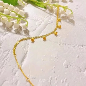 Detail of golden lily of the valley bracelet with delicate floral pendants and fine chain