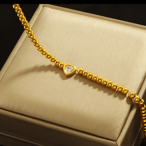 Golden beaded bracelet featuring a sparkling heart zircon charm on a luxury jewelry box
