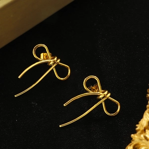 Minimalist golden bow stud earrings with sleek metal lines on an elegant black background