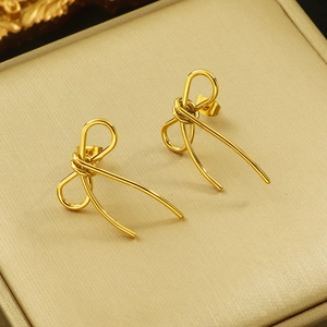 Macro view of gold bow earrings with polished linear design in a luxury jewelry box