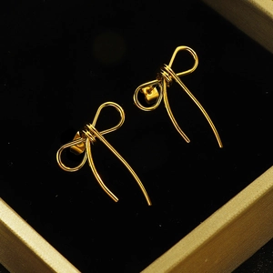 Elegant gold bow earrings with a high-polish finish on black velvet display