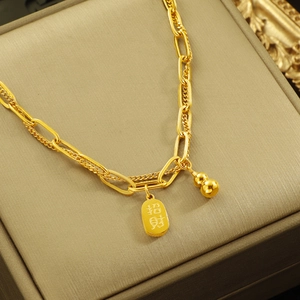 Gold double-layer calabash necklace with lucky charm on a brown jewelry box