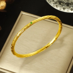 Close-up of gold bangle featuring intricate cloud patterns and a green gemstone inlay