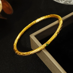 Golden vintage filigree bangle with green gemstone and intricate vine carvings