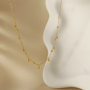 Collier minimaliste à pampilles de grains d'or 18 carats sur support d'art blanc