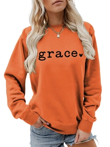 Detail of orange crewneck sweatshirt featuring black grace text and heart print