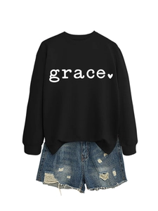 Close-up of black sweatshirt with grace text print and distressed denim shorts detail
