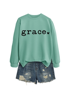 Detail of mint green sweatshirt with grace print paired with distressed denim shorts