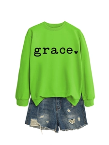Flat lay of neon green crewneck sweatshirt with grace heart print and ripped denim shorts