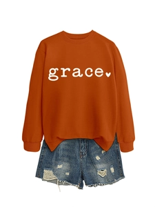Flat lay of an orange crewneck sweatshirt with grace text and ripped denim shorts