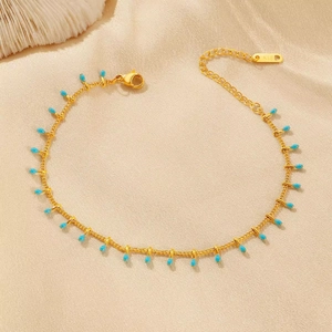 Detailed macro view of a 18K gold-plated anklet with blue enamel teardrop pendants