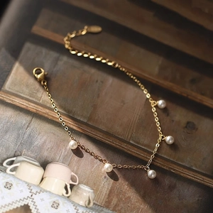 Elegant gold pearl bracelet featuring five white pearls on a delicate minimalist chain