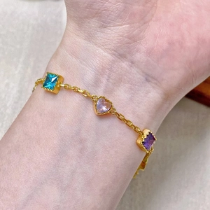Elegant gold bracelet featuring colorful heart and square zircon charms on a model wrist