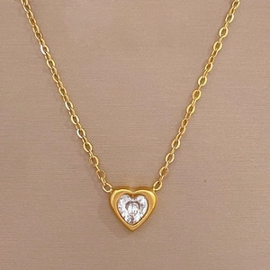 Collier élégant en forme de cœur doré avec pierre en zircone rose sur un fond beige