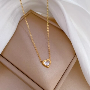 Détail du collier avec pendentif cœur en or et zircon sur une boîte à bijoux dorée