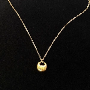 Gros plan du pendentif cadenas de paix doré avec caractère Fu sur tissu noir