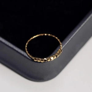Minimalist gold stainless steel ring with nine small cube beads on blue velvet case