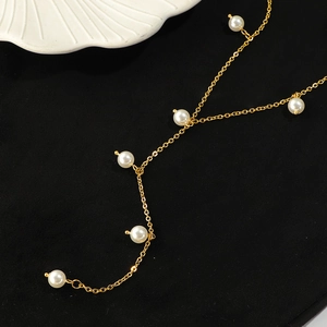 Elegant gold chain necklace with white pearls on a black velvet background