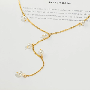 Elegant gold-plated Y-shaped stainless steel necklace with six white pearls on sketchbook