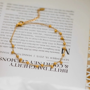 Bracelet de cheville doré élégant avec perles et chaîne réglable sur un magazine
